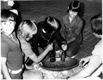 Children crushing something in a wooden bowl