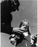 Man showing girl how to hold an arrow for hoop and arrow game