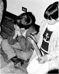 Children sitting on floor, one holding hide scraper by Dan Wooley