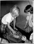 Children grinding grain with mano and metate by Ron Trickel